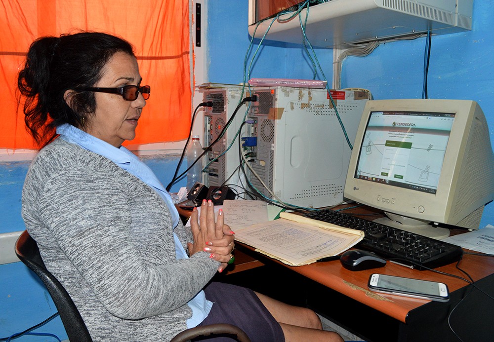 Instructora sentada en computadora de un Joven Club en Santa Clara.