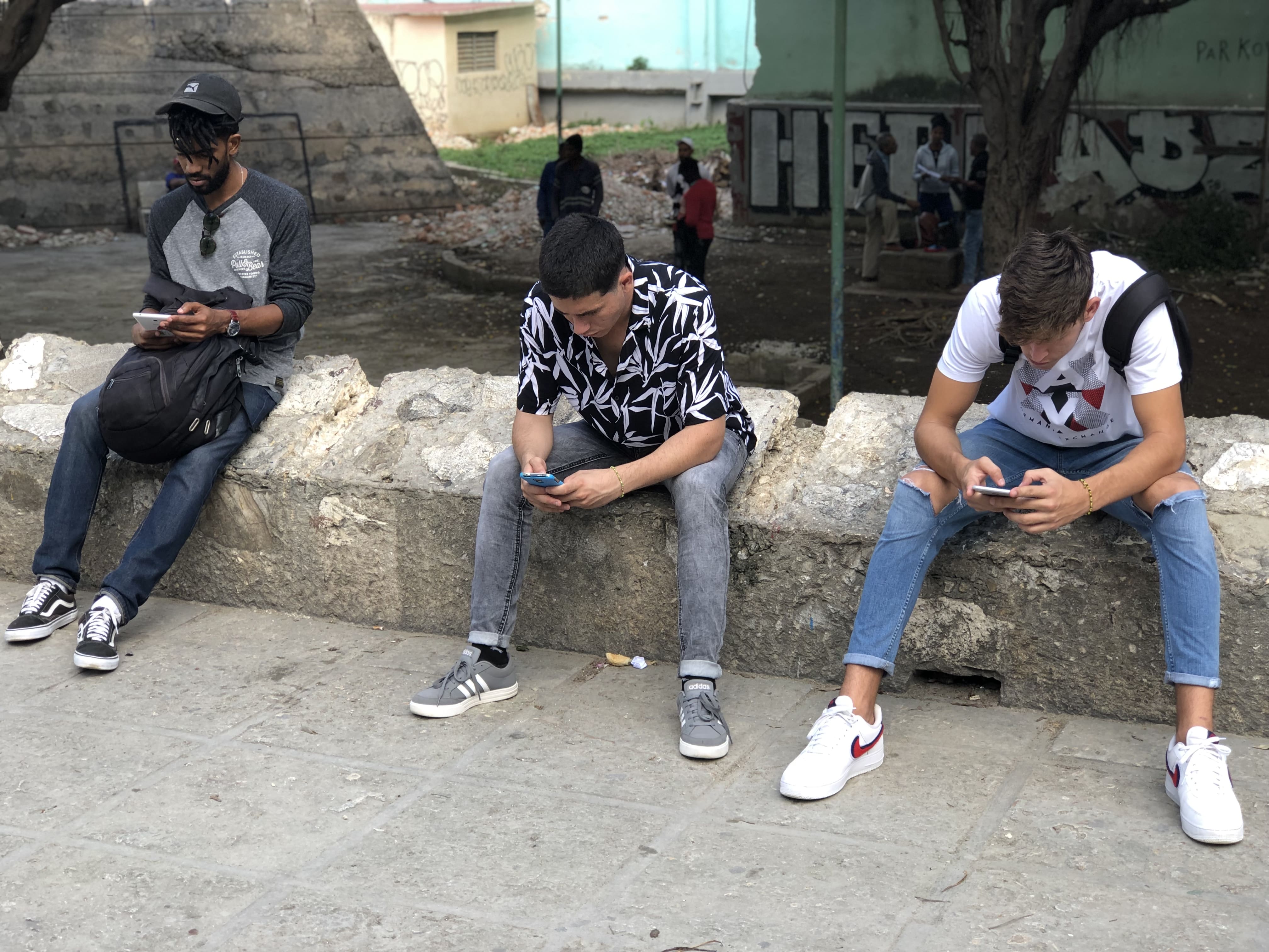 Jóvenes cubanos usan  teléfonos  inteligentes para conectarse a internet en La Habana.