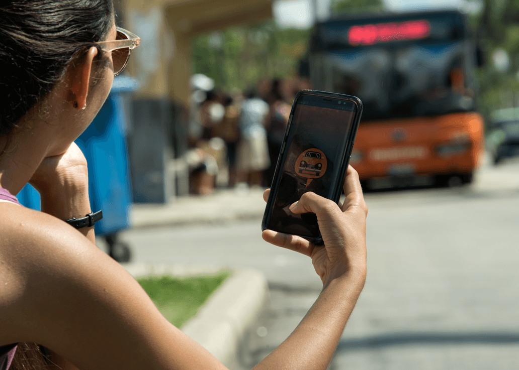 Muchacha sostiene teléfono movil en la calle y en la pantalla puede verse el logotipo de Cuber, otra de las aplicaciones cubanas similares a Uber