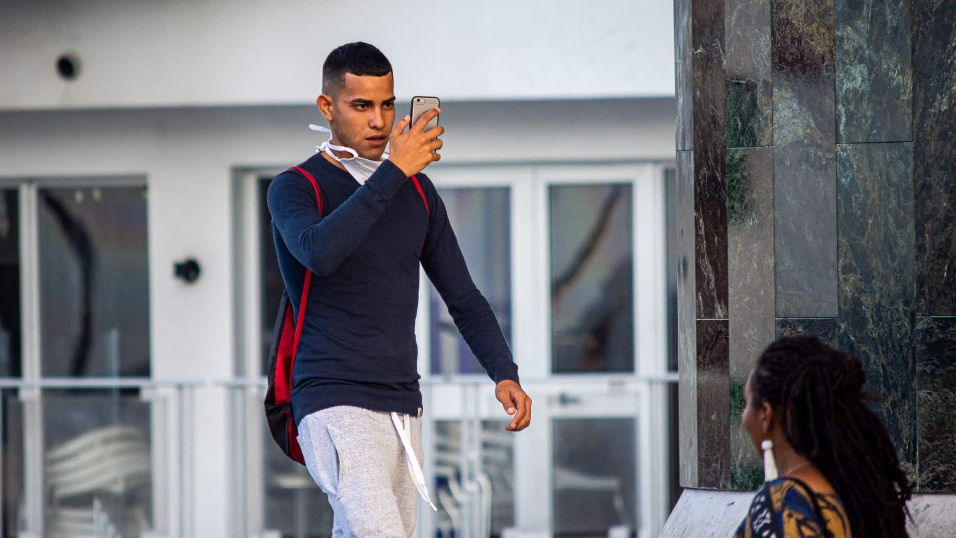 Cubano camina por calle de La Habana con un teléfono inteligente